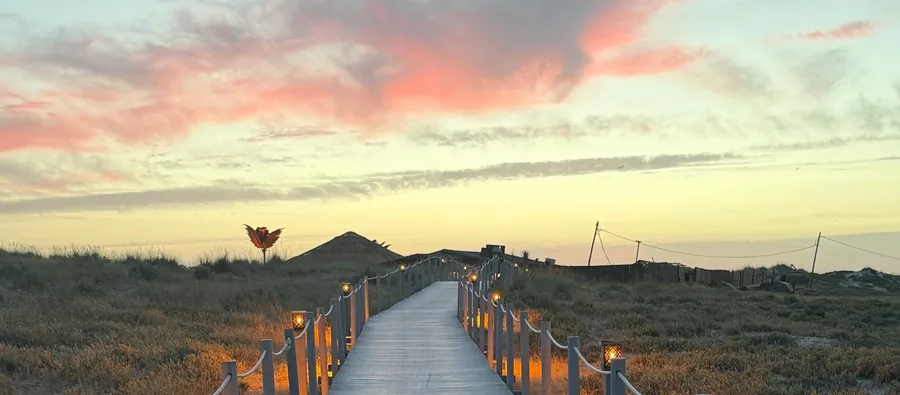 A boardwalk through the dunes of the Costa de Caparica at golden hour.