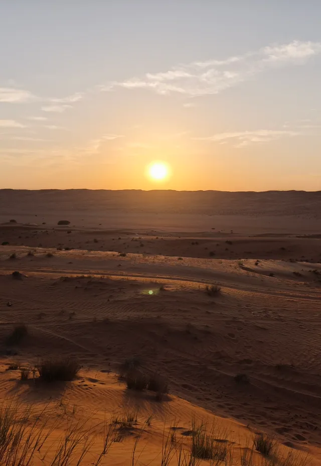 The sun low over the Wahiba Sands dunes, Oman.